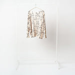 Bluză bej cu croială lejeră, imprimeu simpatic cu pisici negre și mâneci lungi, fotografiată frontal pe umeraș.