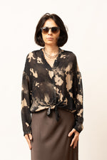 Detaliu frontal al bluzei cu imprimeu abstract în tonuri de negru și bej.