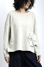 Bluză largă din jerse de bumbac, cu croială rândunică și aplicație floare la bază, în nuanță deschisă.