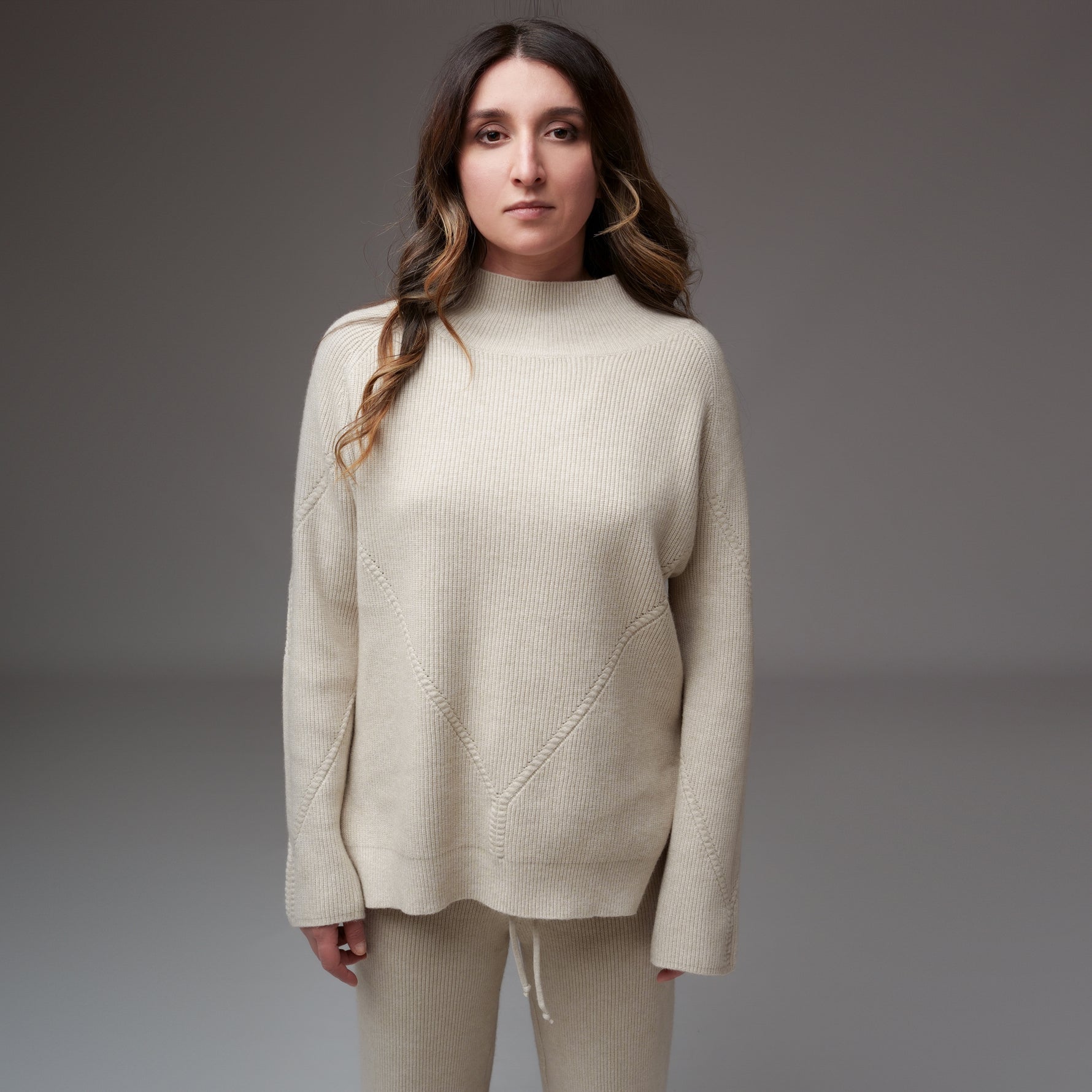 Bluză crem din tricot raiat cu model ajurat și guler turtleneck, văzută din față