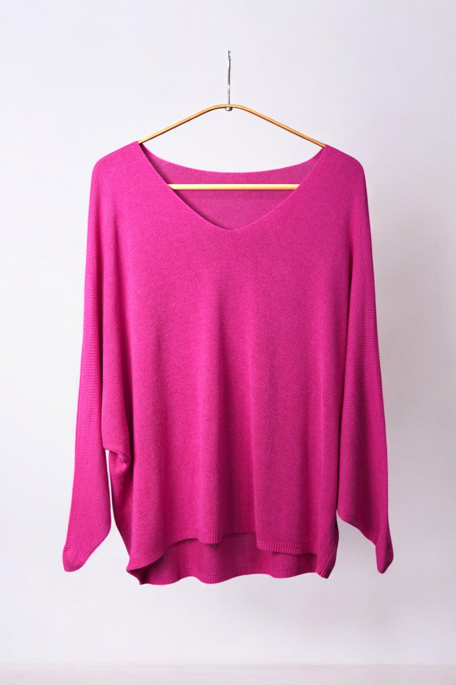 Bluză vibrantă din tricot fucsia, cu decolteu în V și mâneci trei sferturi, pe umeraș.