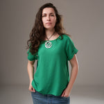 Bluză verde smarald lejeră din viscoză, cu mâneci scurte și guler rotund, purtată de model cu colier rotund