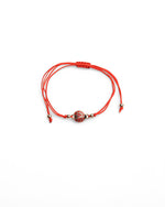 Brățară reglabilă roșie cu pandantiv în formă de gândăcel buburuză, simbol al norocului.