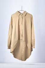 Cămașă asimetrică bej din bumbac, cu nasturi albi și croială lejeră.