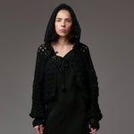 Capă stil bolero croșetată din acril negru, cu glugă supradimensionată și șireturi groase decorative, purtată peste rochie neagră.