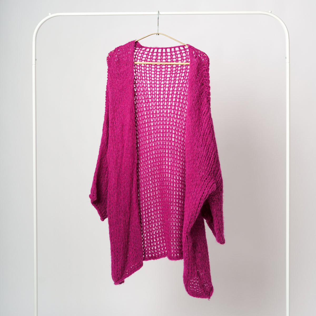 Cardigan fucsia midi croșetat cu ochiuri largi și umeri căzuți, expus pe umeraș