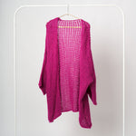 Cardigan fucsia midi croșetat cu ochiuri largi și umeri căzuți, expus pe umeraș