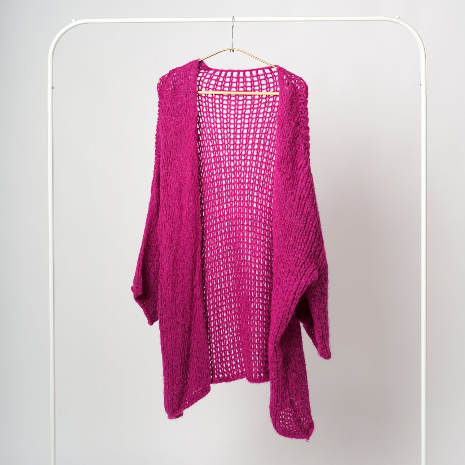 Cardigan fucsia midi croșetat cu ochiuri largi și umeri căzuți, expus pe umeraș