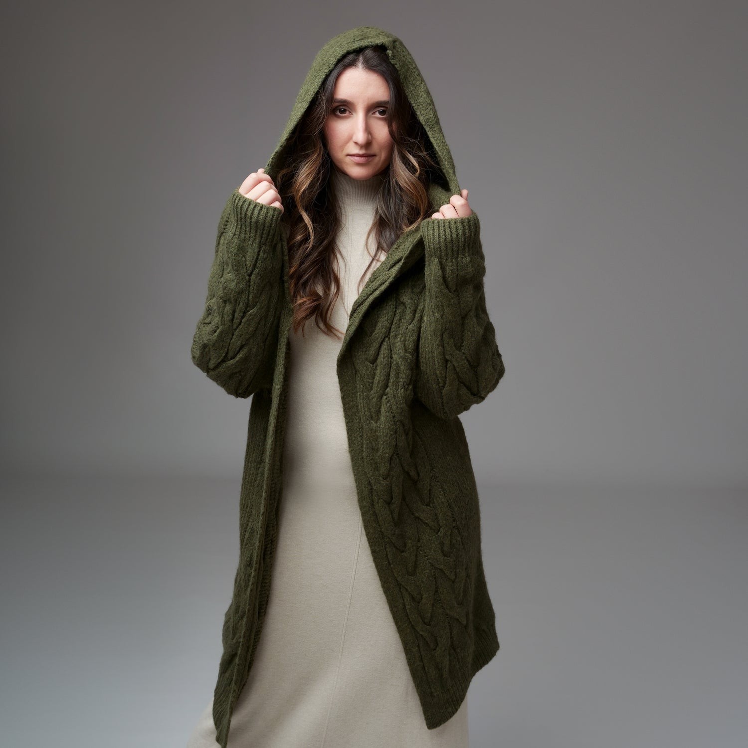 Cardigan lung tricotat kaki, cu glugă, purtat lejer peste rochie bej, vedere frontală.