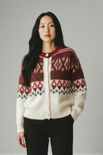 Cardigan pufos cu model nordic în nuanțe de roșu, verde și crem, purtat într-o ținută casual.