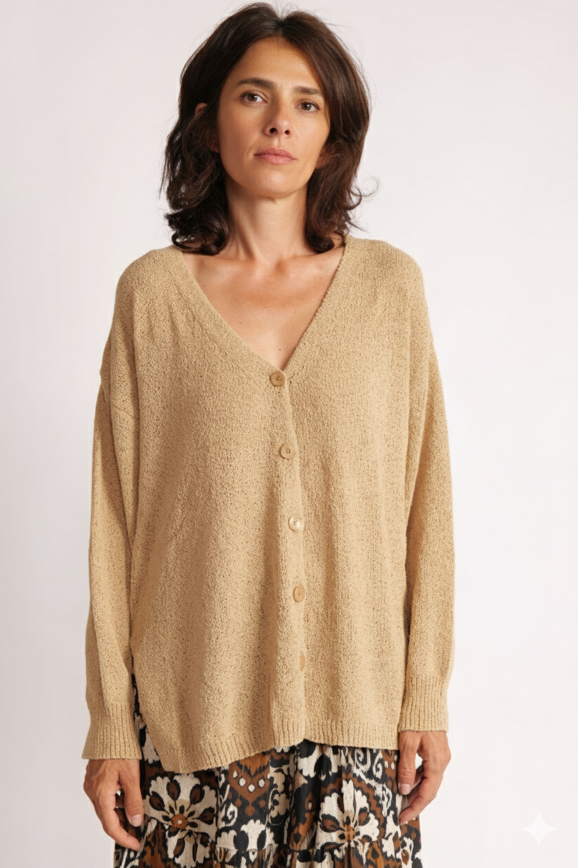 Cardigan bej din țesătură tip sac, cu decolteu în V, mânecă lungă și croială lejeră, purtat de model.