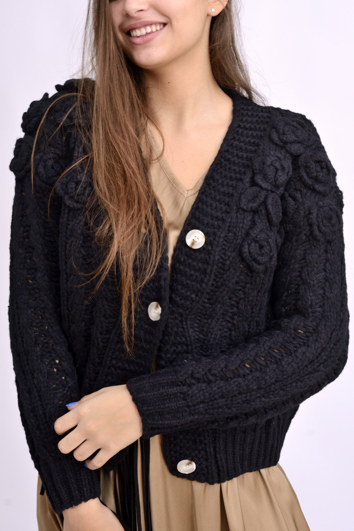 Detaliu al texturii tricotate cu flori mari reliefate și nasturi decorativi.