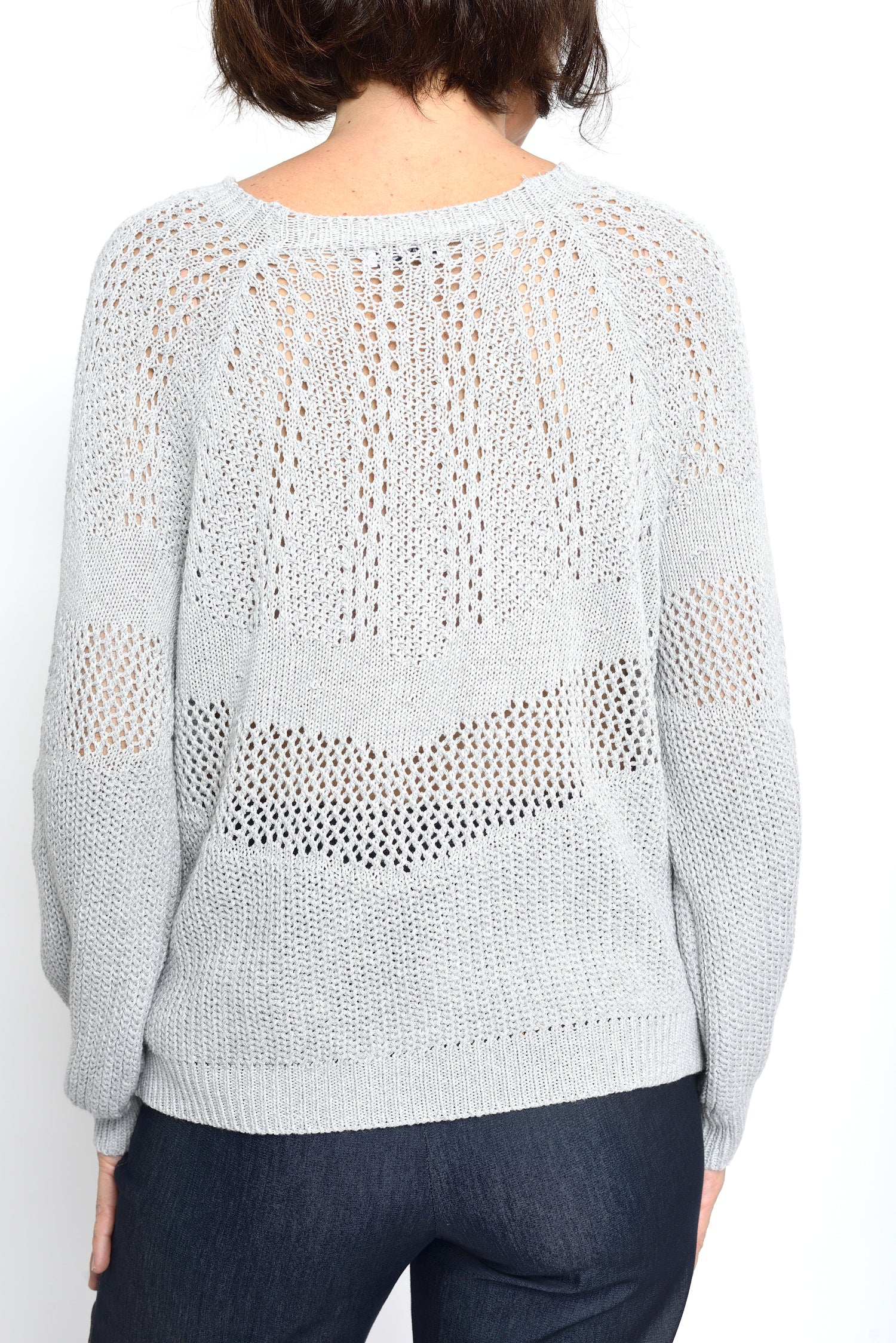 Spatele unui cardigan gri tricotat cu model perforat decorativ și croială lejeră.