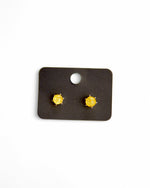 Cercei bobițe cu piatră galbenă, expuși pe suport negru