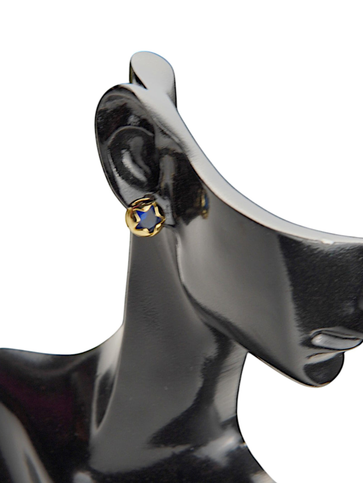 Cercei buton aurii cu piatră în formă de steluță albastră, purtați pe un manechin negru lucios.