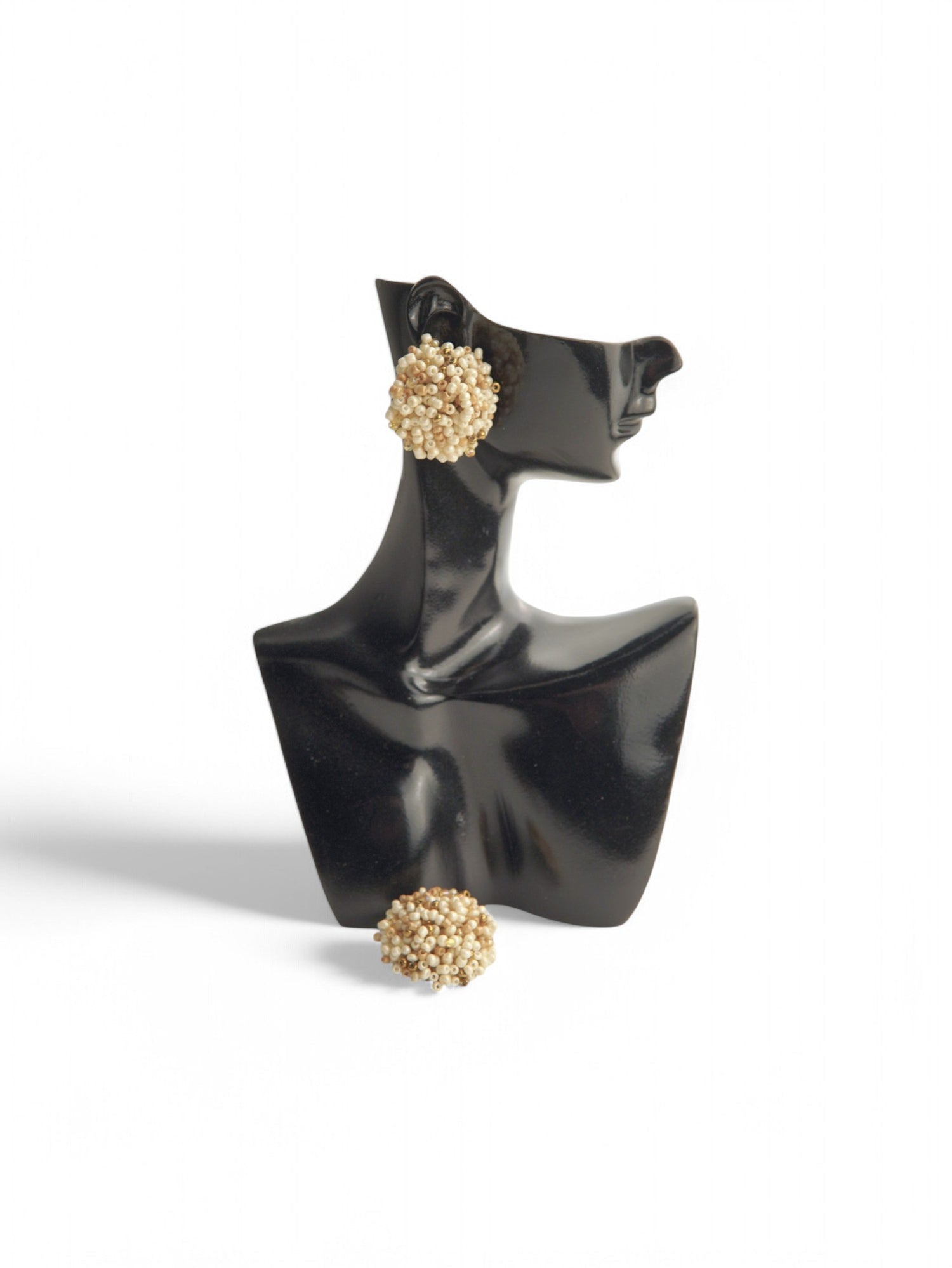 Cercei butoni crem prezentați pe un suport de model, scoțând în evidență dimensiunea și designul unic.