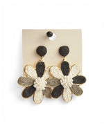 Cercei in forma de floare, cu petale alb-negru si detalii aurii elegante.