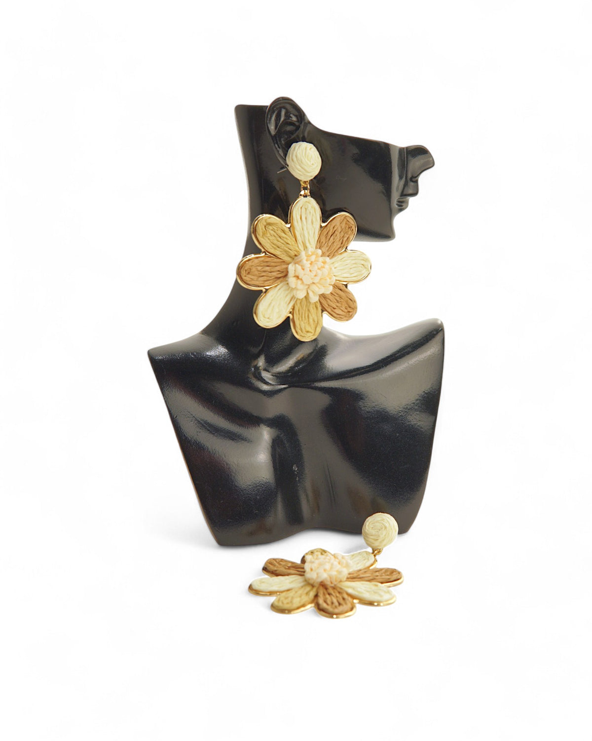 Cercei creponati in forma de floare, nuante crem si bej, prezentati pe suport elegant.