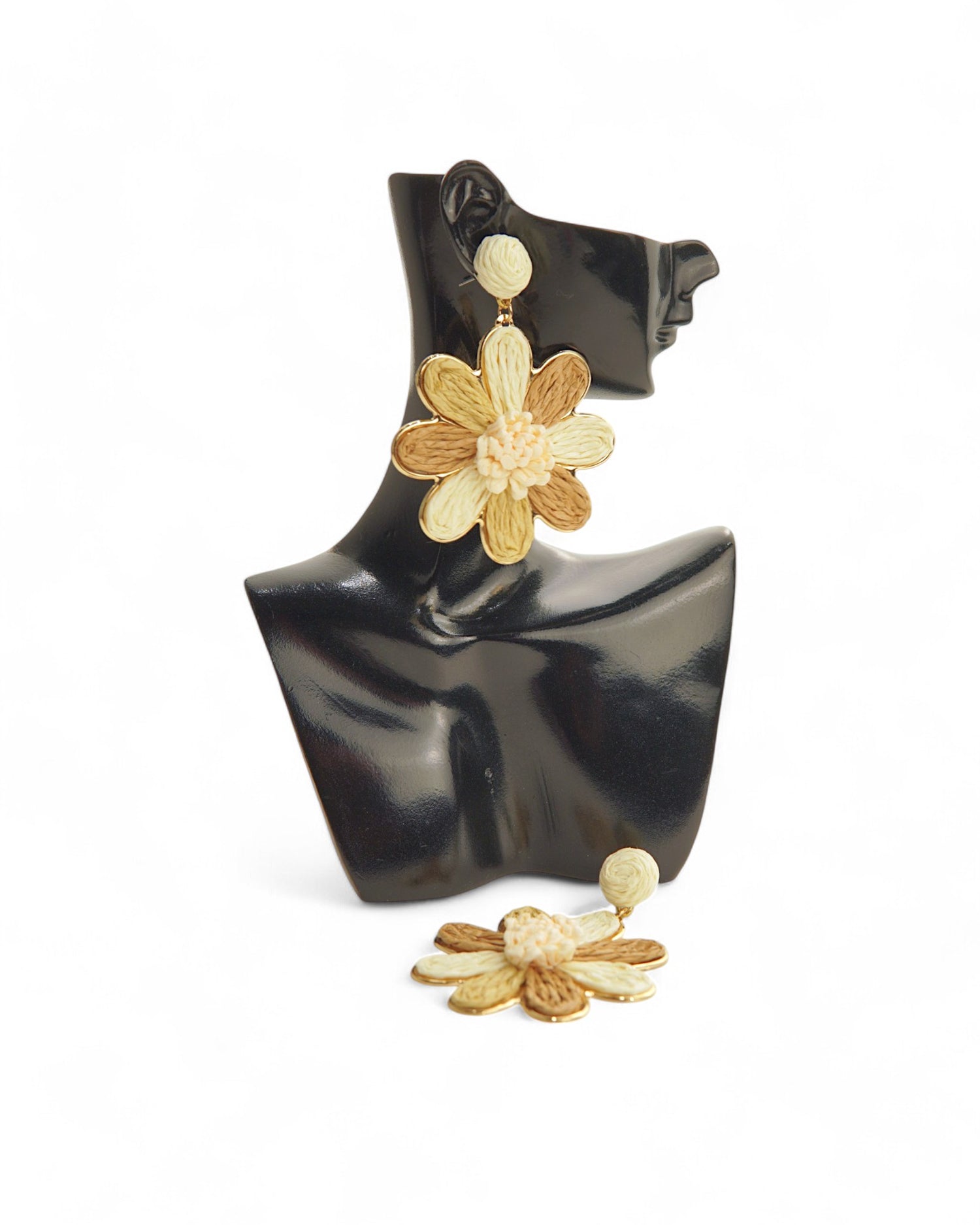 Cercei creponati in forma de floare, nuante crem si bej, prezentati pe suport elegant.