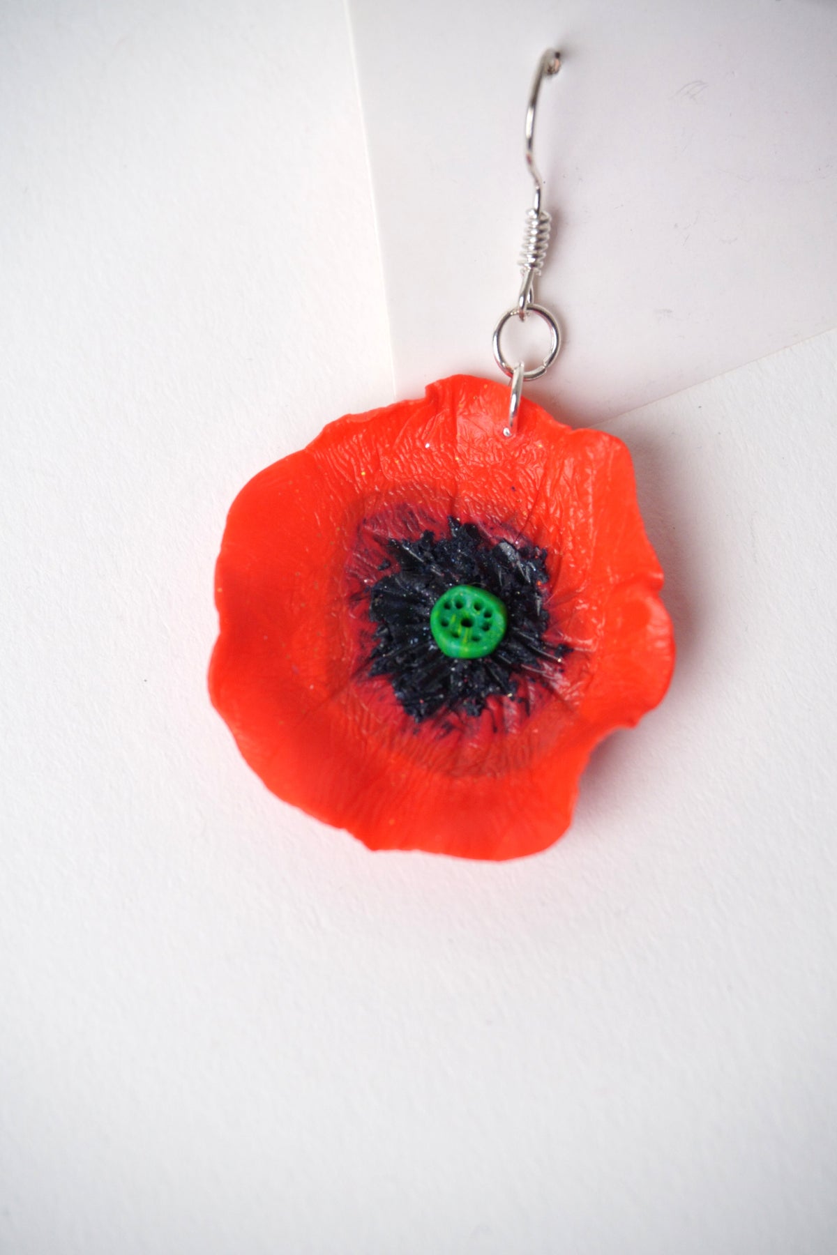 Detaliu cercei handmade în formă de floare de mac roșu, modelați manual din fimo.