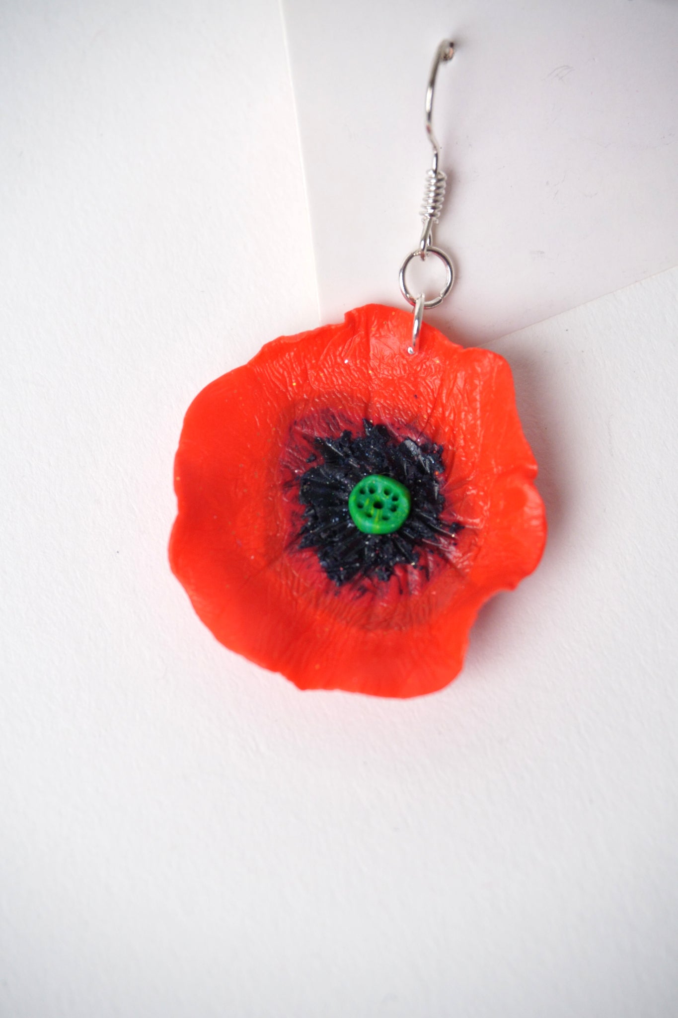 Detaliu cercei handmade în formă de floare de mac roșu, modelați manual din fimo.