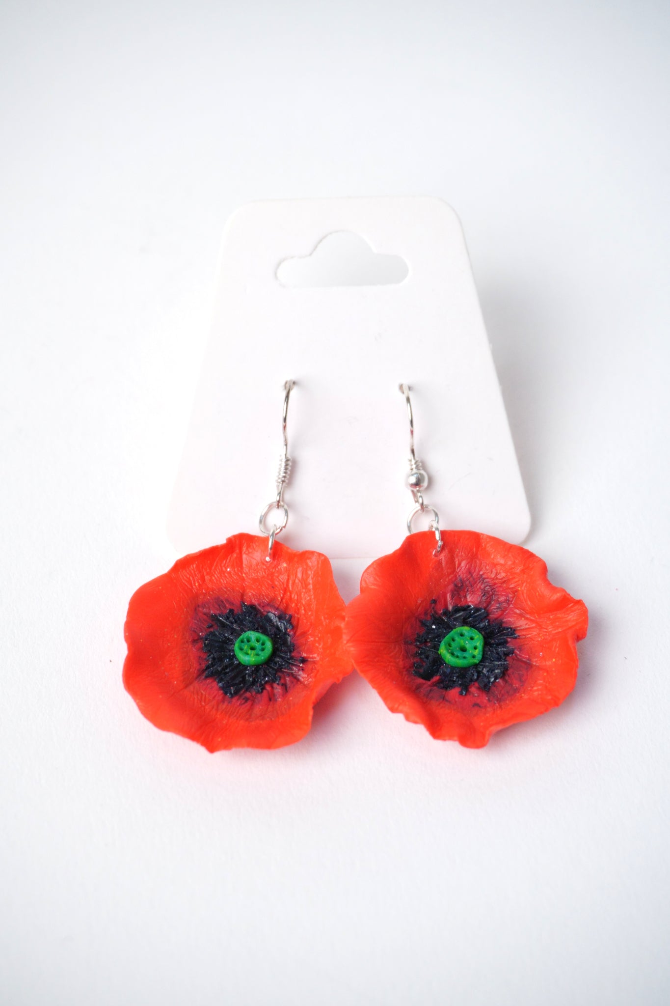 Cercei handmade din fimo, în formă de mac roșu, cu detalii negre și verzi în centru.