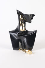 Cercei lungi aurii din metal, formă răsucită sculpturală, cu închidere tip șurub, prezentați pe suport de expunere.