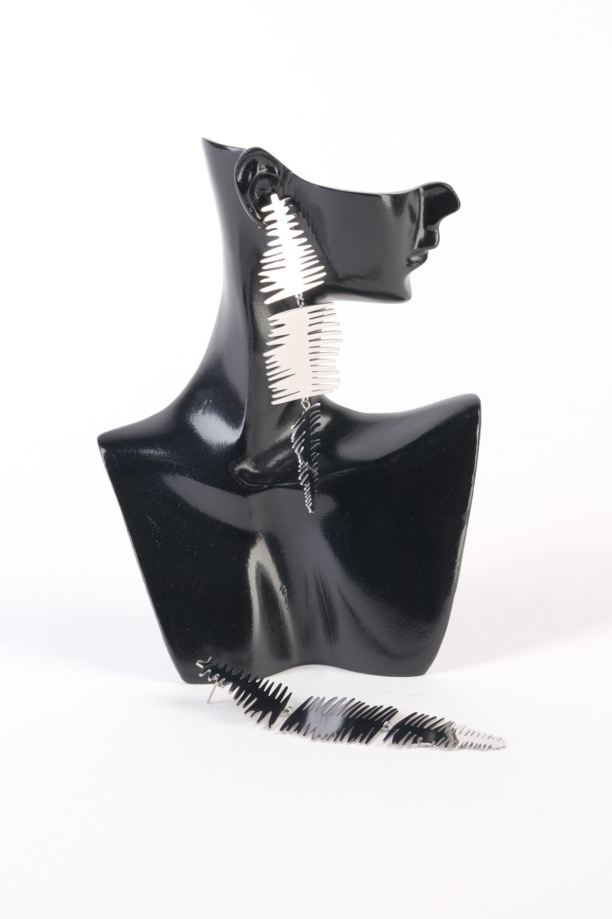 Cercei lungi argintii din oțel inoxidabil, cu margini zimțate pe trei segmente, prezentați pe suport de expunere.