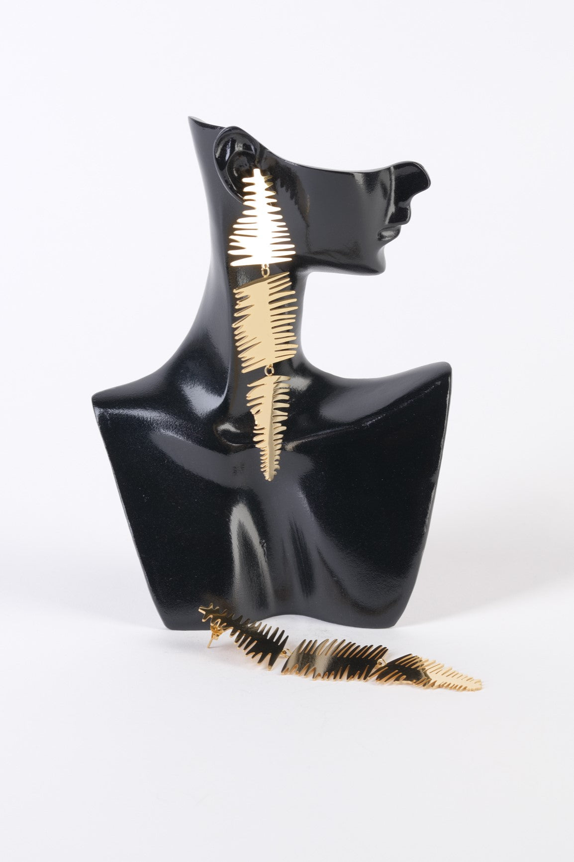 Cercei lungi aurii din oțel inoxidabil, cu margini zimțate pe trei segmente, prezentați pe suport de expunere.