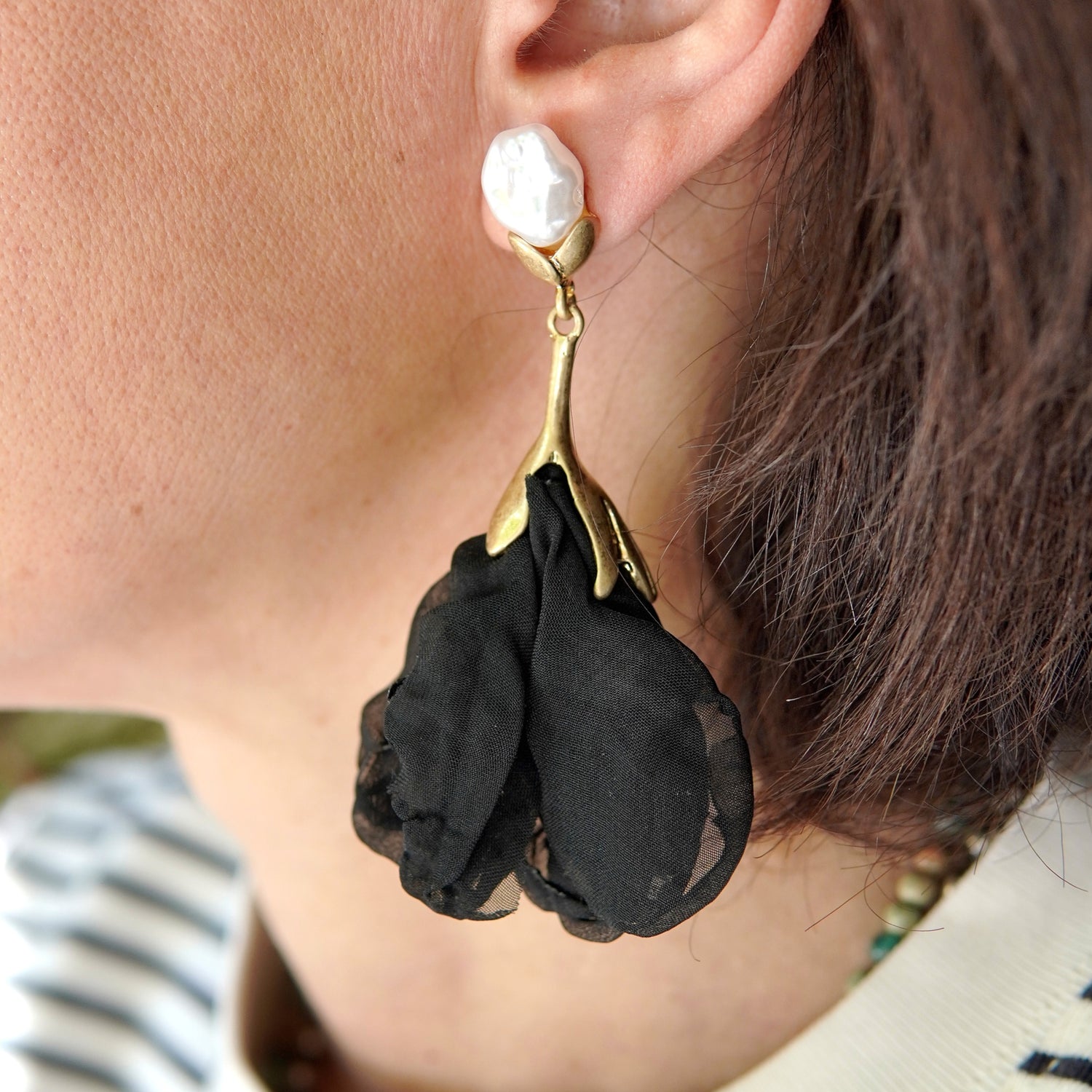 Cercei cu perlă albă și floare textilă satinat negru, din oțel inoxidabil, purtați la ureche.