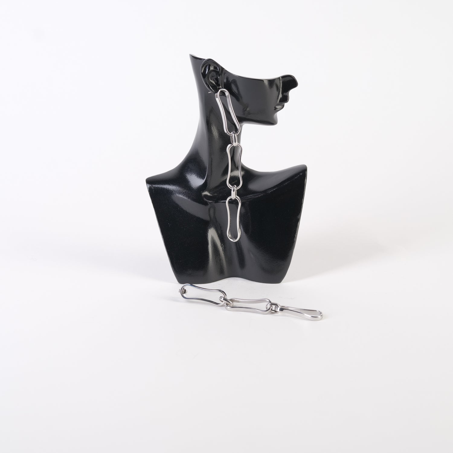 Cercei lungi din zale metalice, design statement, expuși pe un suport negru