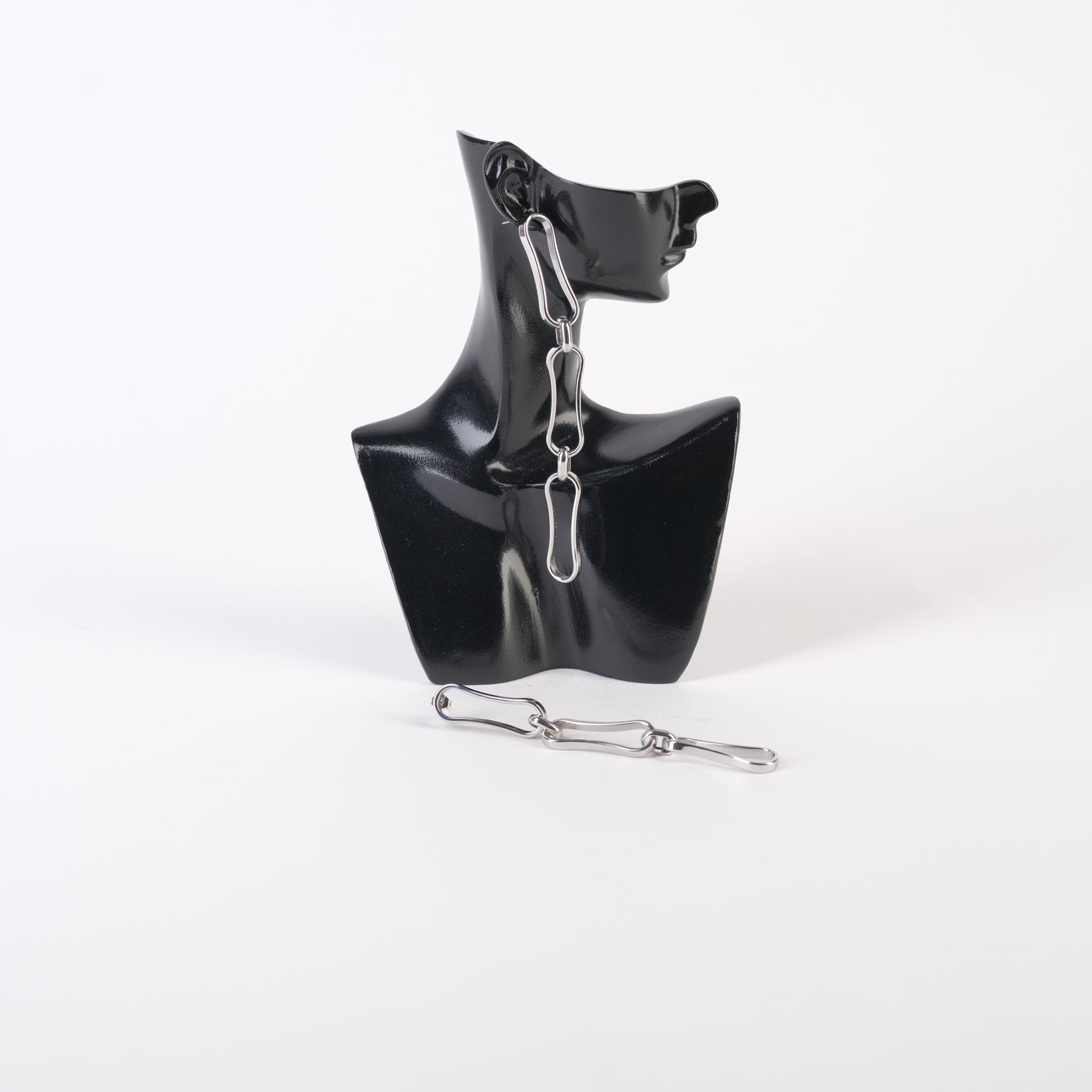 Cercei lungi din zale metalice, design statement, expuși pe un suport negru