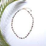 Colier fin cu cristale bordo și perluțe albe, accesorii aurii din oțel inoxidabil, vedere de ansamblu pe fundal alb.