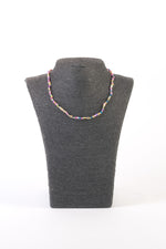 Colier cu perle de cultură mici, colorate și neregulate, prezentat pe suport negru, cu închidere metalică tip carabină.