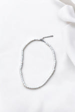 Colier cu perle de cultură văzut de sus, așezat în formă ovală pe fundal alb, cu prelungire vizibilă.