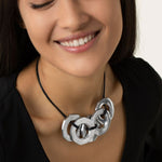 Colier scurt cu 5 piulițe mari din aluminiu reciclat, purtat de o femeie care zâmbește, pe un șnur negru reglabil