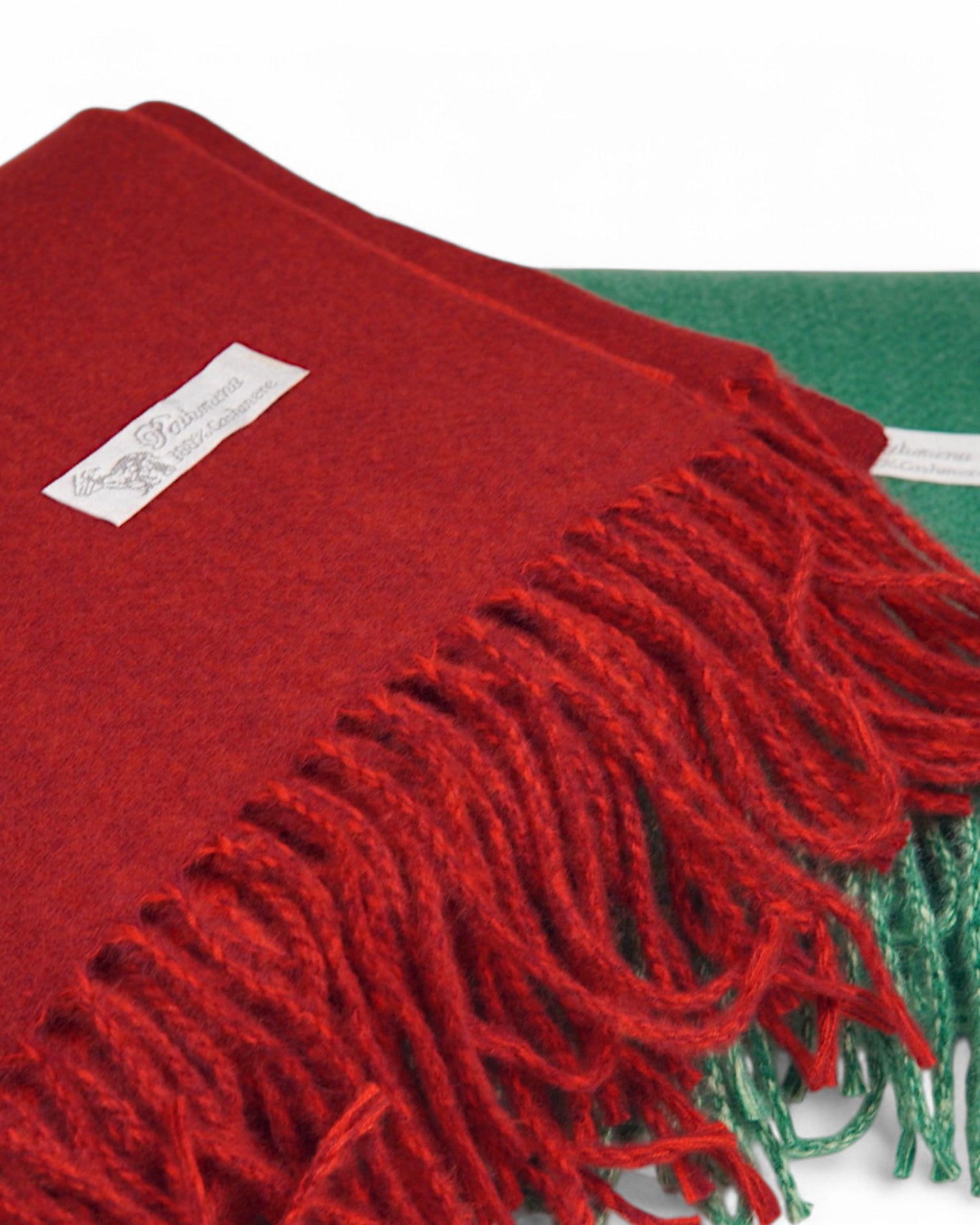 Detaliu al fularului pashmina roșu, evidențiind textura fină și franjurii decorativi.