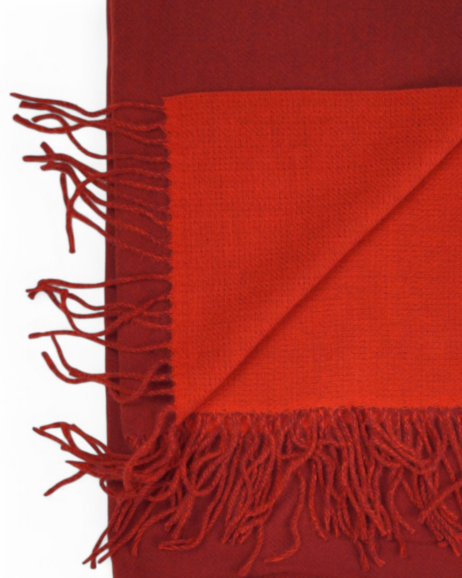 Gros-plan pe franjurii fini ai fularului pashmina roșu, material texturat și dens.