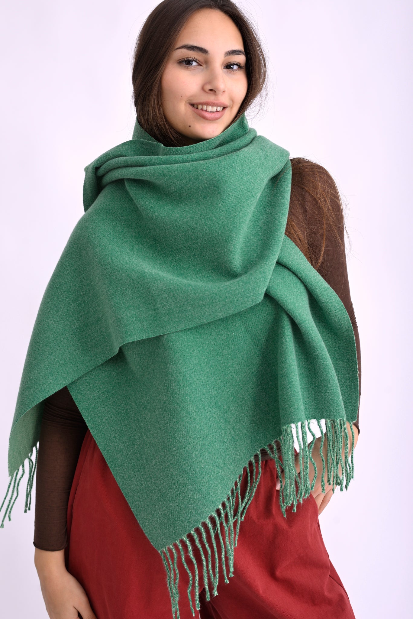 Model poartă un fular pashmina verde, din material moale cu franjuri, înfășurat elegant pe umeri.