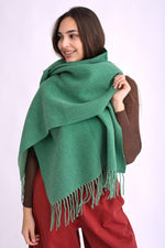 Fular pashmina verde, fotografiat din lateral, cu aspect fluid și călduros.