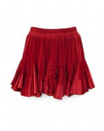 Detaliu al volanelor fustei scurte din catifea roșie, cu o textură luxuriantă și elegantă.