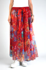 Fustă roșie cu imprimeu floral purtată cu pantofi sport albi, vedere din față