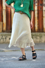 Textura naturală, plisată, a unei fuste midi beige din bumbac și mătase, cu tiv ușor evazat.