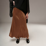 Material lucios cognac al unei fuste midi satinate, cu textură fluidă și croi evazat