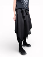 Vedere laterală a fustei negre cu tul, cu suprapuneri și tiv neregulat.