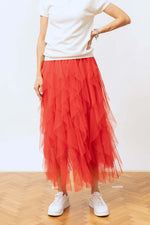 Fustă din tulle roșu cu volane multiple, vedere frontală, asortată cu tricou alb și pantofi sport albi.