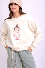 Hanorac crem cu imprimeu artistic reprezentând o fetiță mirată, croială lejeră, purtat pe model.