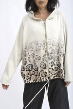 Hanorac cu glugă, croială lejeră și umeri căzuți, purtat într-o ținută casual.