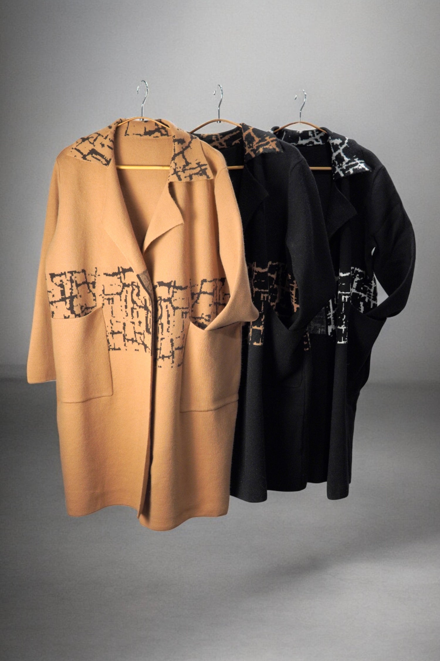 Paltoane bej și negre cu imprimeu abstract, expuse pe umerașe pentru prezentarea culorilor disponibile.