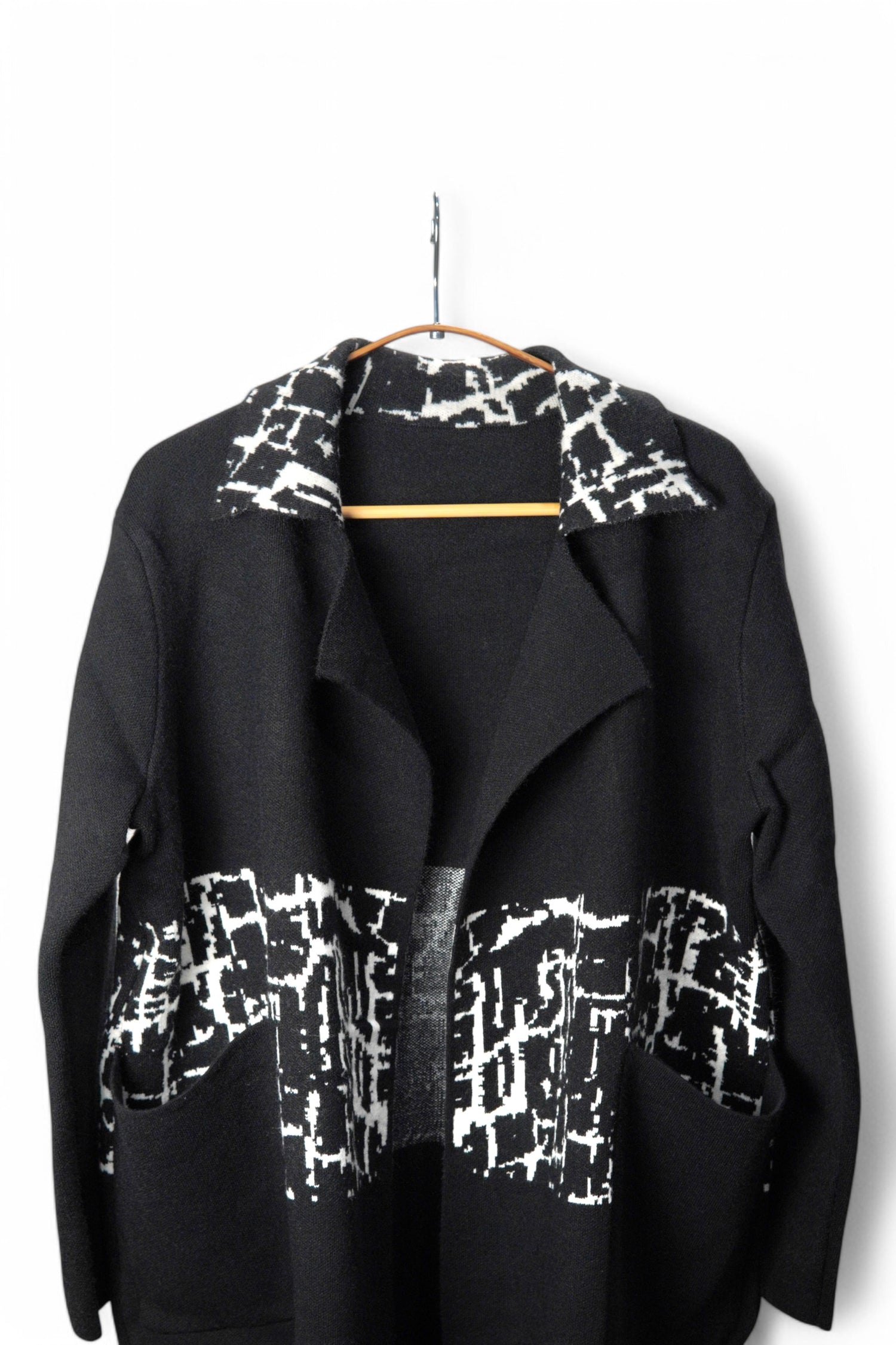 Detaliu al gulerului paltonului negru cu imprimeu alb, design modern și elegant.